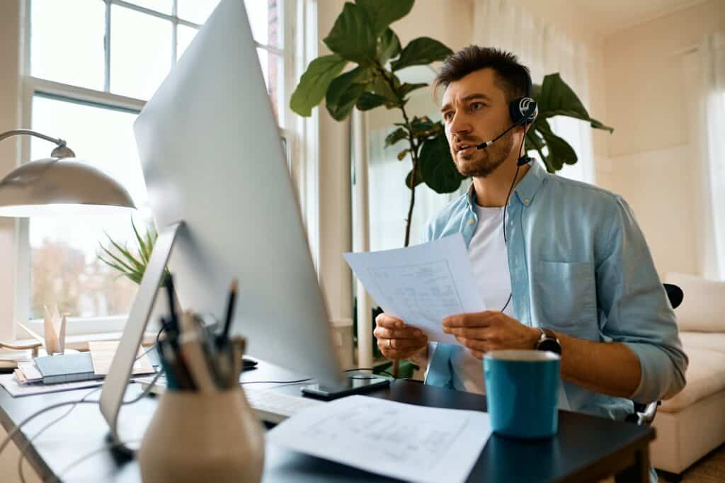 Businessman talking during online video meeting while working at home office.